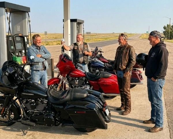 Quatre motards discutent à la station-service, motos équipées de SelleZen